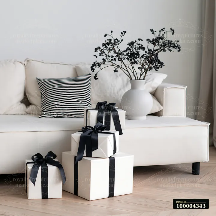 Wrapped gifts with black ribbons are placed beside a modern sofa in a bright living room.