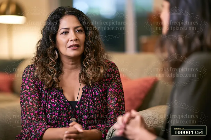 Therapist listens attentively to a person seated in a warmly lit counseling setting.