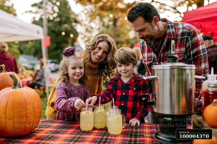 Parents and two children share lemonade at a pumpkin-decorated outdoor fall festival.