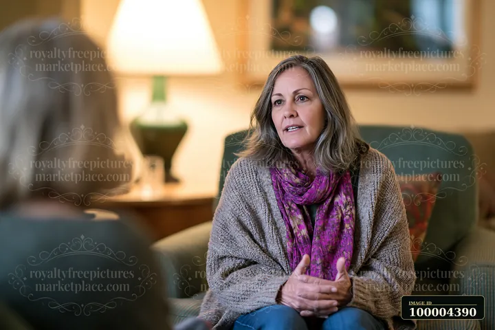 Woman speaks with a therapist during a supportive counseling session in a warmly lit living room.