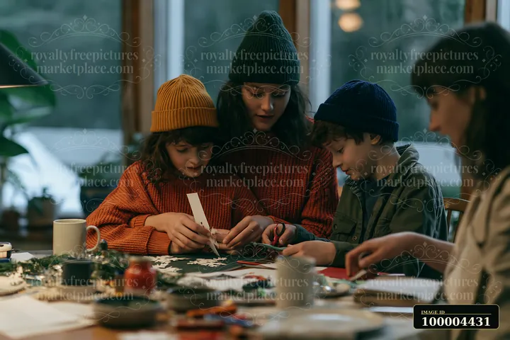 Family members make paper snowflakes together at a warmly lit indoor craft table.
