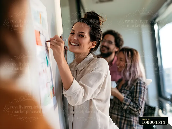 A female manager writes on a whiteboard during a brainstorming session.