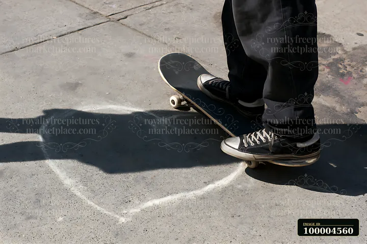 Skateboarder standing over a white chalk outline on sunlit cracked pavement