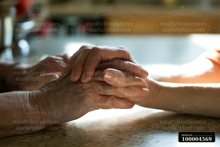 Two hands gently intertwine in a close-up view on a tabletop in warm indoor light.